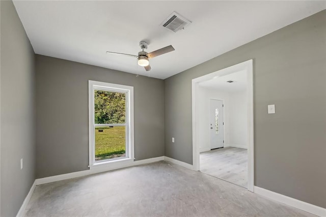 spare room featuring ceiling fan, visible vents, and baseboards