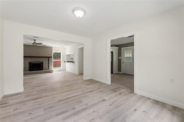 unfurnished living room featuring ceiling fan, a wealth of natural light, light wood-type flooring, and a brick fireplace