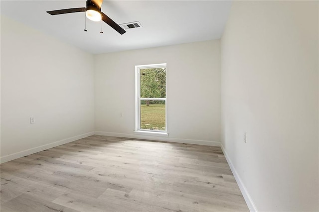 spare room featuring light wood finished floors, baseboards, visible vents, and a ceiling fan