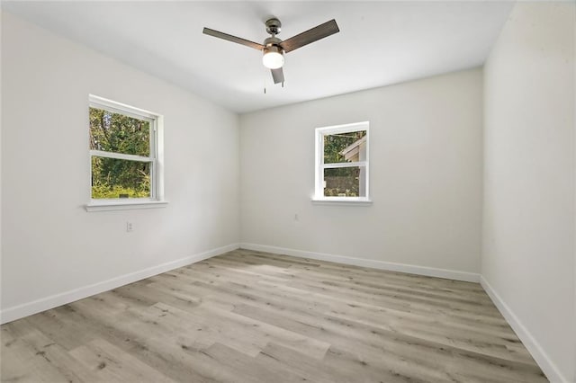 empty room with ceiling fan, light wood-type flooring, and a wealth of natural light