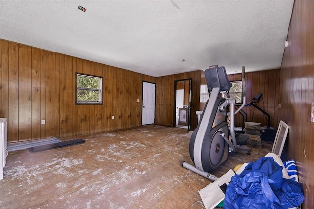 workout area featuring a textured ceiling and wood walls