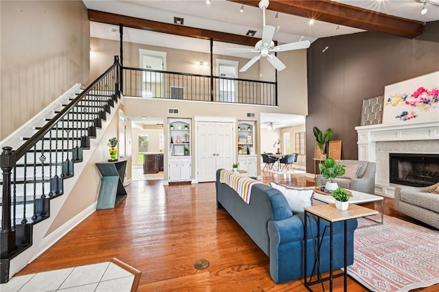 living room featuring hardwood / wood-style floors, ceiling fan, a towering ceiling, and beamed ceiling