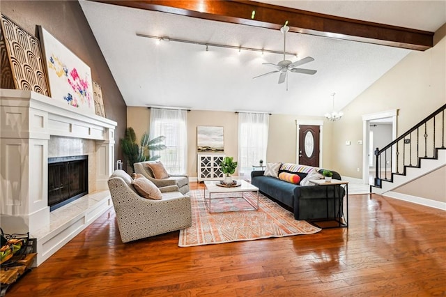 living room with ceiling fan, rail lighting, beamed ceiling, wood-type flooring, and a fireplace