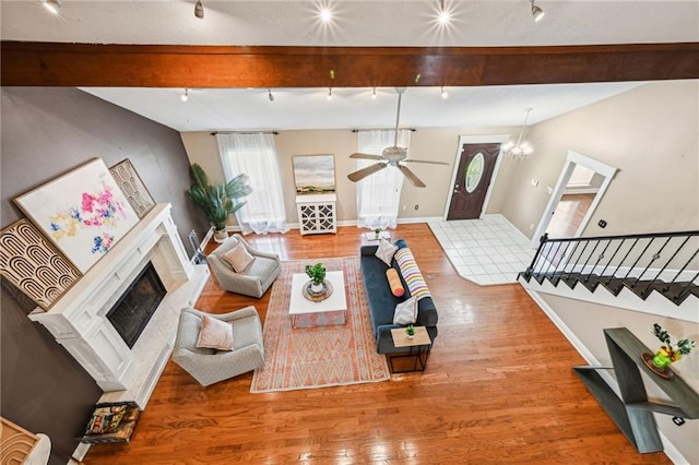 living room featuring hardwood / wood-style floors, ceiling fan with notable chandelier, and beam ceiling