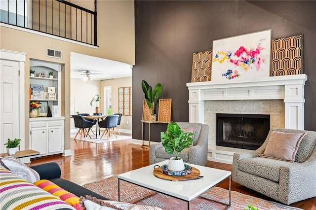 living room featuring ceiling fan, built in features, and wood-type flooring