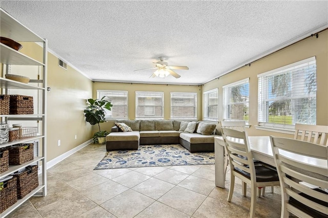 tiled living room featuring ceiling fan, ornamental molding, a textured ceiling, and a wealth of natural light