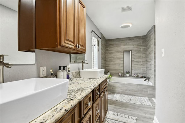 bathroom with hardwood / wood-style floors, vanity, and tiled bath