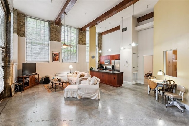 living area featuring ceiling fan, a towering ceiling, beamed ceiling, and concrete flooring