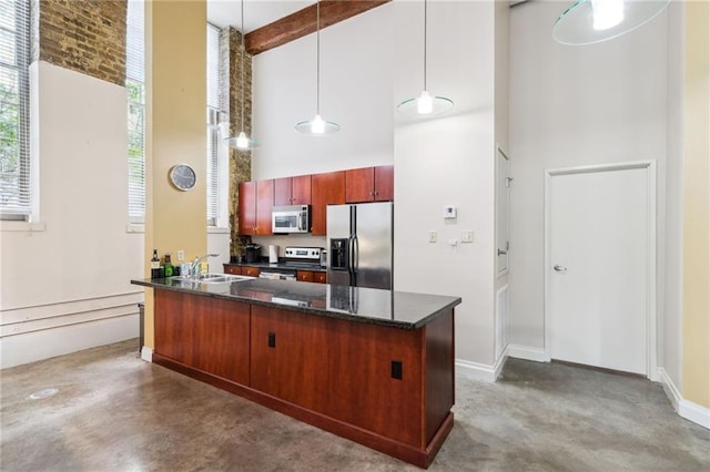 kitchen with pendant lighting, sink, a towering ceiling, appliances with stainless steel finishes, and concrete flooring