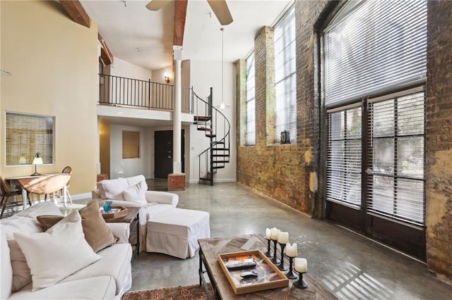 living room with concrete floors, ceiling fan, and a high ceiling