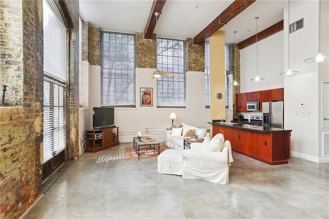 interior space featuring concrete flooring, ceiling fan, brick wall, beam ceiling, and a high ceiling