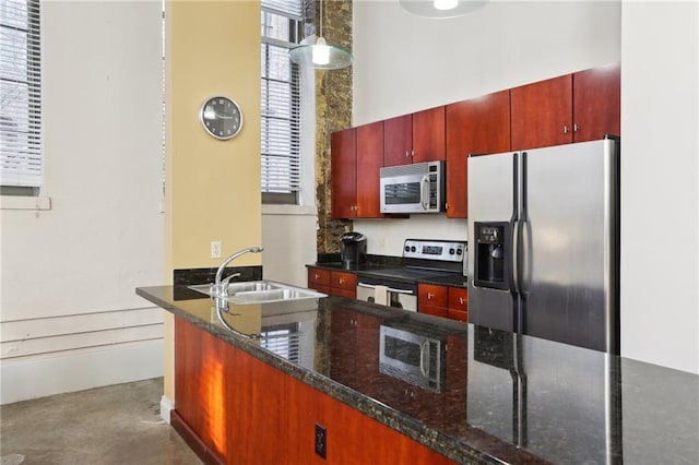 kitchen with sink, stainless steel appliances, kitchen peninsula, decorative light fixtures, and dark stone counters