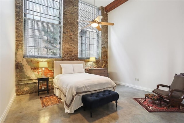 bedroom featuring brick wall, beam ceiling, concrete floors, and a high ceiling