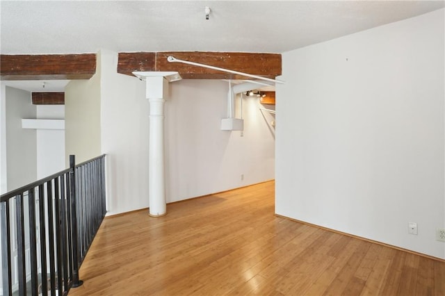 empty room featuring hardwood / wood-style flooring and beamed ceiling