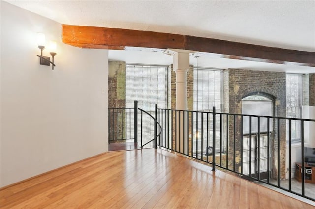 unfurnished room with wood-type flooring and beam ceiling