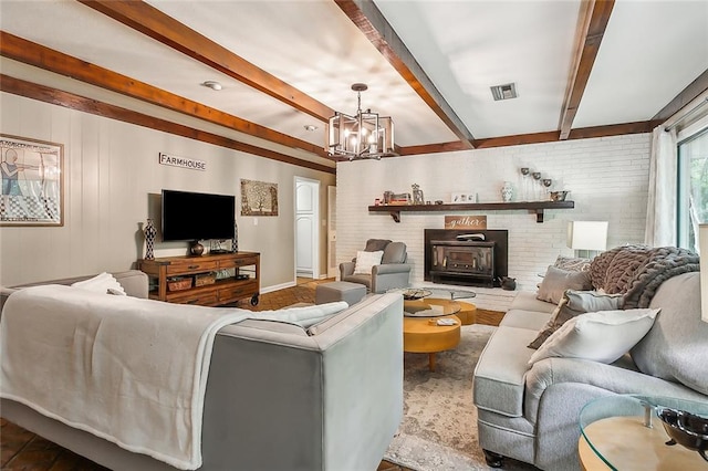 living room featuring a notable chandelier, beam ceiling, and a wood stove