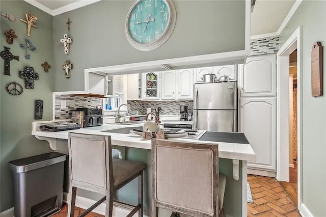 kitchen with a kitchen breakfast bar, kitchen peninsula, tasteful backsplash, and stainless steel fridge