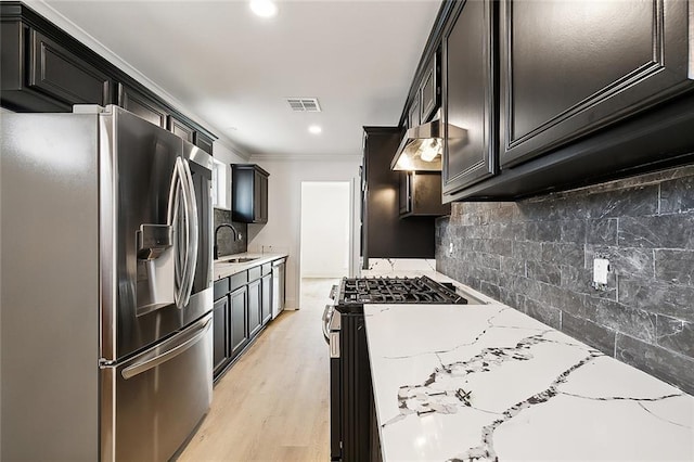 kitchen with ornamental molding, appliances with stainless steel finishes, light stone countertops, light hardwood / wood-style floors, and decorative backsplash