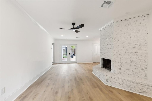 unfurnished living room featuring light hardwood / wood-style flooring, a brick fireplace, ornamental molding, ceiling fan, and french doors