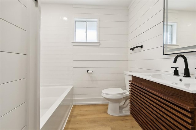 full bathroom with wood walls, vanity, washtub / shower combination, hardwood / wood-style flooring, and toilet