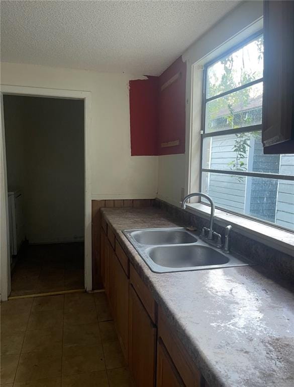 kitchen with a textured ceiling, sink, and dark tile patterned flooring