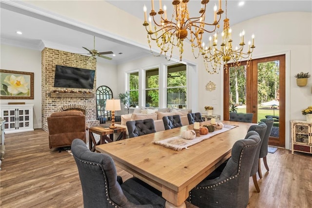 dining room featuring hardwood / wood-style flooring, a fireplace, ornamental molding, and a healthy amount of sunlight