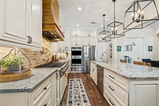 kitchen featuring hanging light fixtures, stainless steel appliances, premium range hood, a kitchen island with sink, and sink