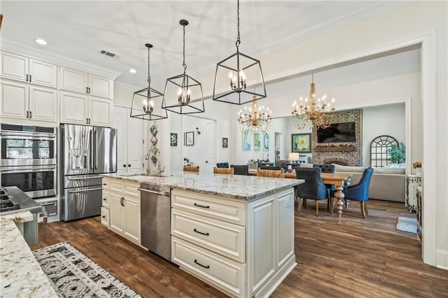 kitchen with light stone counters, appliances with stainless steel finishes, a fireplace, and decorative light fixtures