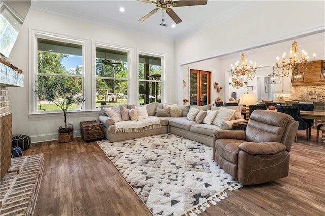 living room with ceiling fan with notable chandelier, ornamental molding, dark wood-type flooring, and a wealth of natural light