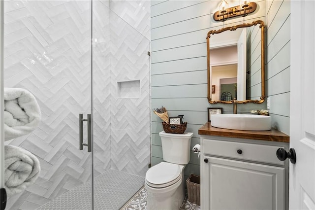 bathroom with wood walls, vanity, a shower with shower door, and toilet