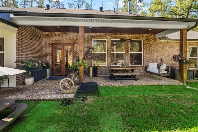 rear view of property featuring a yard, french doors, and a patio area