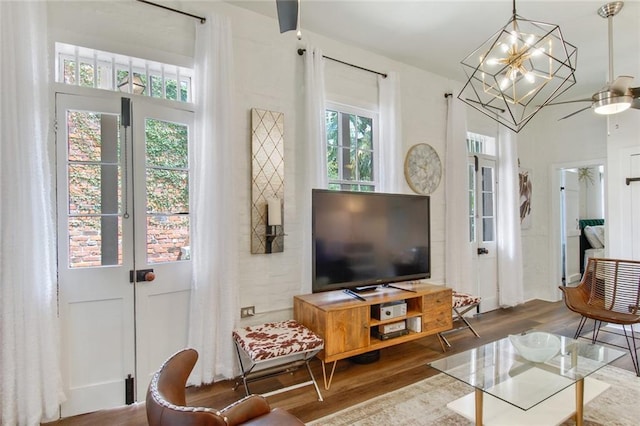 living room with ceiling fan with notable chandelier, plenty of natural light, and wood-type flooring