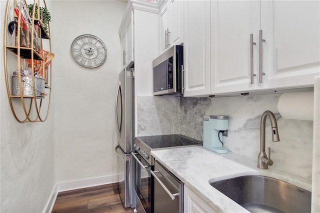 kitchen with stainless steel appliances, white cabinetry, sink, and light stone counters