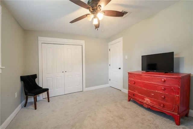 bedroom with ceiling fan, light colored carpet, and a closet