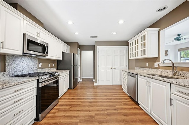 kitchen featuring ceiling fan, white cabinets, sink, appliances with stainless steel finishes, and light wood-type flooring