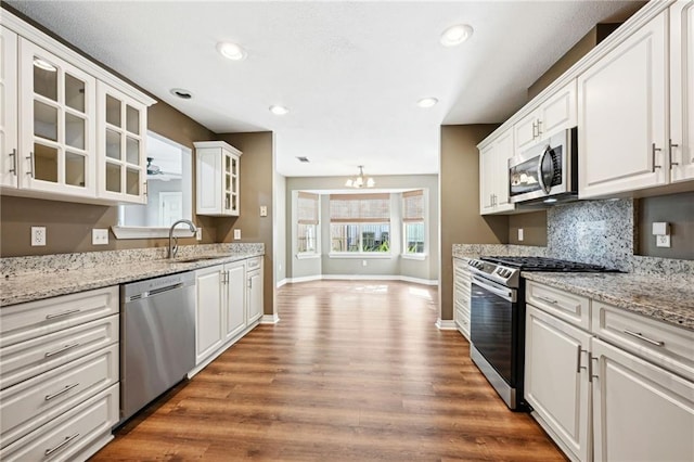 kitchen featuring appliances with stainless steel finishes, wood-type flooring, sink, and white cabinets