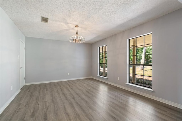 unfurnished room featuring a chandelier, wood-type flooring, and a textured ceiling