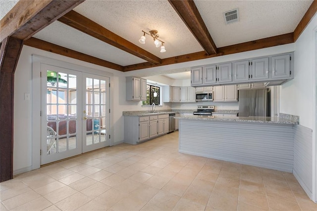 kitchen with french doors, a textured ceiling, stainless steel appliances, sink, and beam ceiling