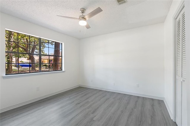 unfurnished bedroom featuring ceiling fan, light wood-type flooring, a textured ceiling, and a closet