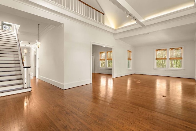 73527 Military Rd, Covington, LA 70435 - unfurnished living room featuring track lighting, baseboards, stairway, wood finished floors, and a towering ceiling