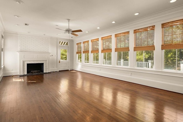 73527 Military Rd, Covington, LA 70435 - unfurnished living room with healthy amount of natural light, a ceiling fan, ornamental molding, a brick fireplace, and dark wood-style flooring