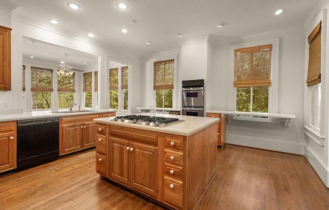 kitchen featuring sink, light wood-type flooring, a kitchen island, stainless steel appliances, and crown molding