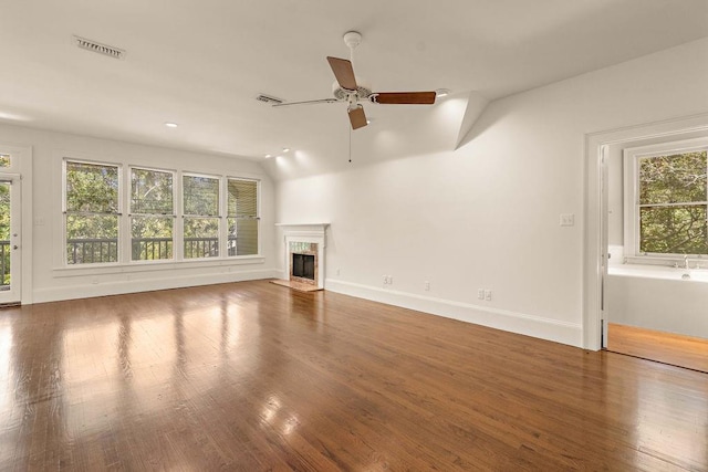 unfurnished living room featuring a premium fireplace, hardwood / wood-style flooring, ceiling fan, and a wealth of natural light