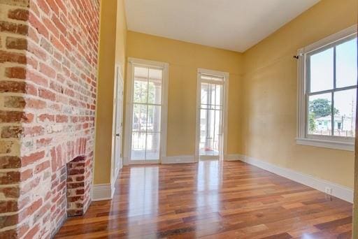 doorway to outside with wood-type flooring, plenty of natural light, and brick wall