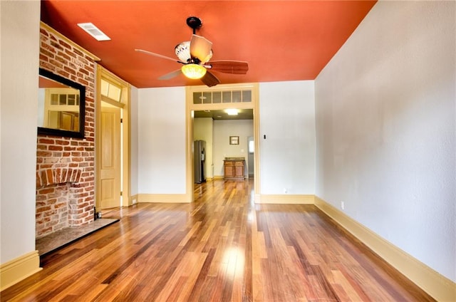 unfurnished room with water heater, ceiling fan, and hardwood / wood-style flooring