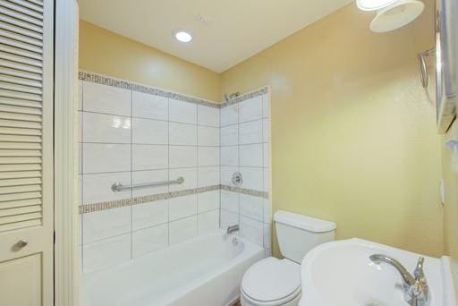 bathroom featuring tiled shower / bath combo and toilet