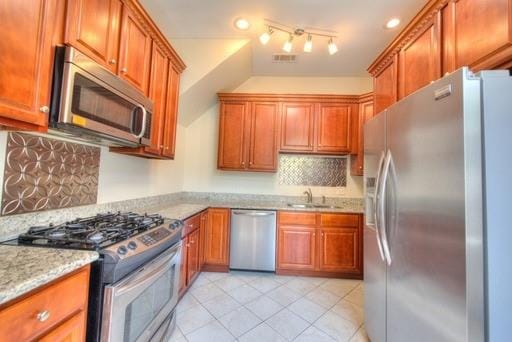 kitchen with light stone counters, sink, stainless steel appliances, backsplash, and light tile patterned floors