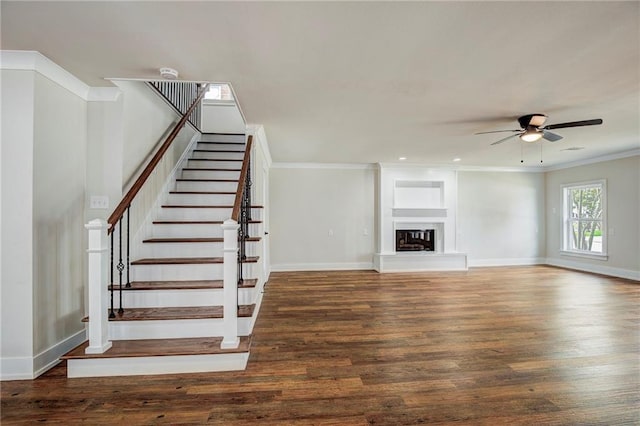 unfurnished living room featuring ceiling fan, dark hardwood / wood-style floors, ornamental molding, and built in features