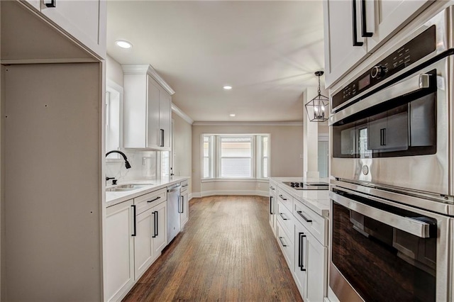 kitchen with dark hardwood / wood-style floors, sink, white cabinetry, hanging light fixtures, and stainless steel appliances