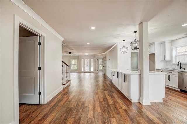 kitchen with hanging light fixtures, stainless steel dishwasher, white cabinetry, ceiling fan with notable chandelier, and dark hardwood / wood-style flooring